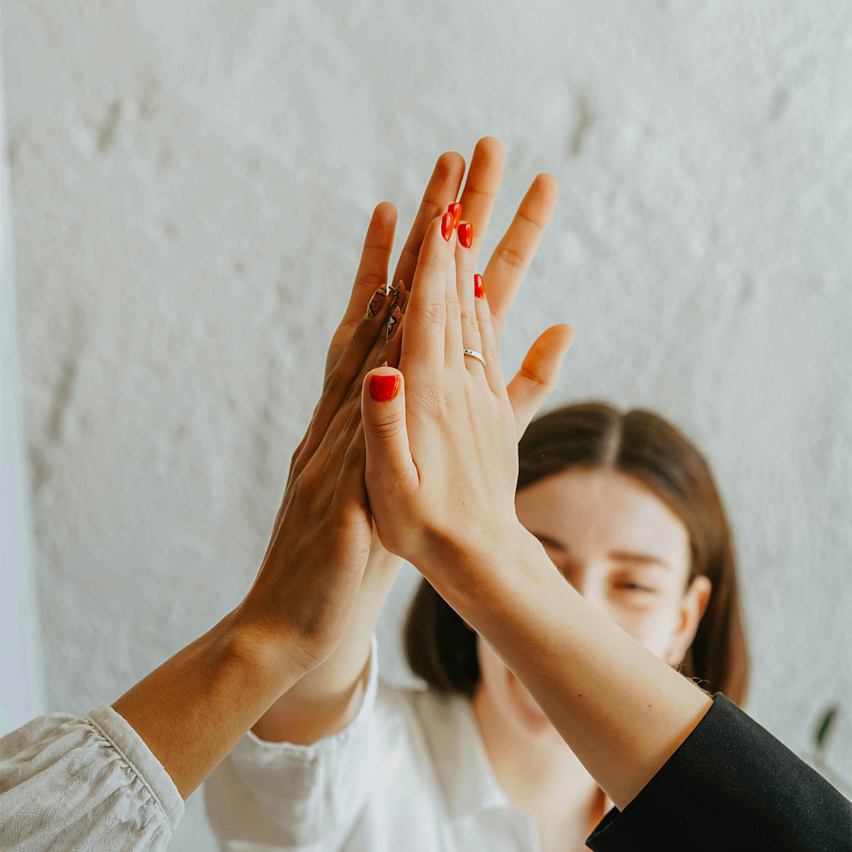 Trois femmes se tapant dans la main pour représenter la bienveillance, une valeur forte au cœur d'Ysalie Beauté