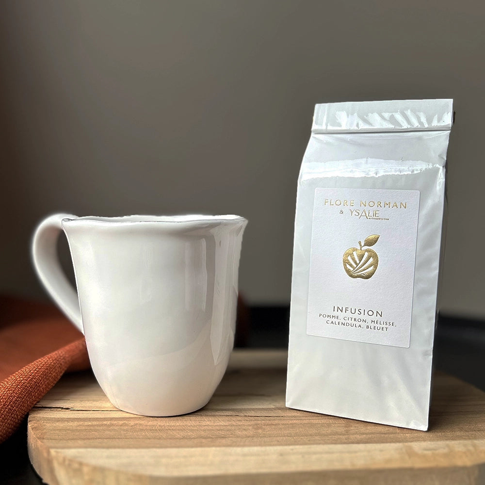Recharge de l'Infusion Beauté présenté sur un socle en bois et à côté d'une tasse blanche.